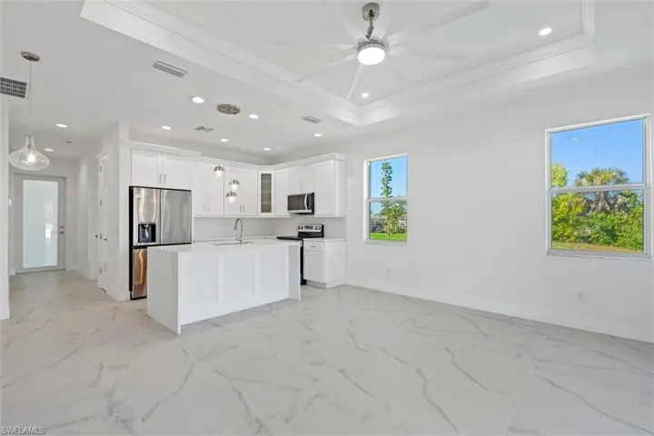 Kitchen featuring recessed lighting, a sink, stainless steel appliances, glass insert cabinets, and a raised ceiling