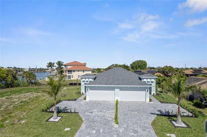 View of front of home featuring decorative driveway, a water view, a garage, and a front yard