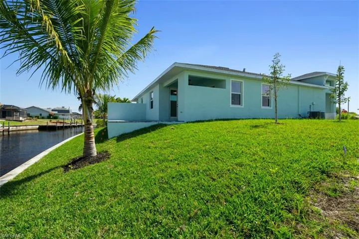 Back of property featuring a yard, cooling unit, a water view, and stucco siding