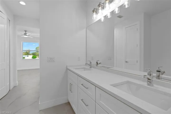 Full bath with double vanity, baseboards, visible vents, and a sink