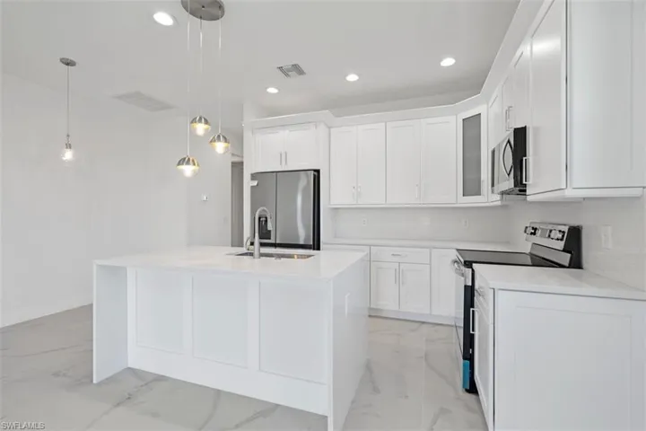 Kitchen featuring visible vents, marble finish floor, an island with sink, appliances with stainless steel finishes, and white cabinets