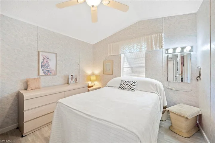 Bedroom with ceiling fan, lofted ceiling, light wood-style flooring, a textured ceiling, and wallpapered walls