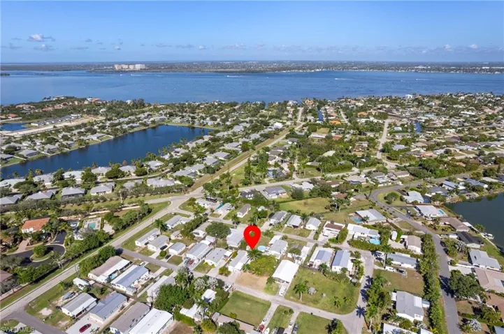 Aerial view of property and surrounding area featuring nearby suburban area and a large body of water