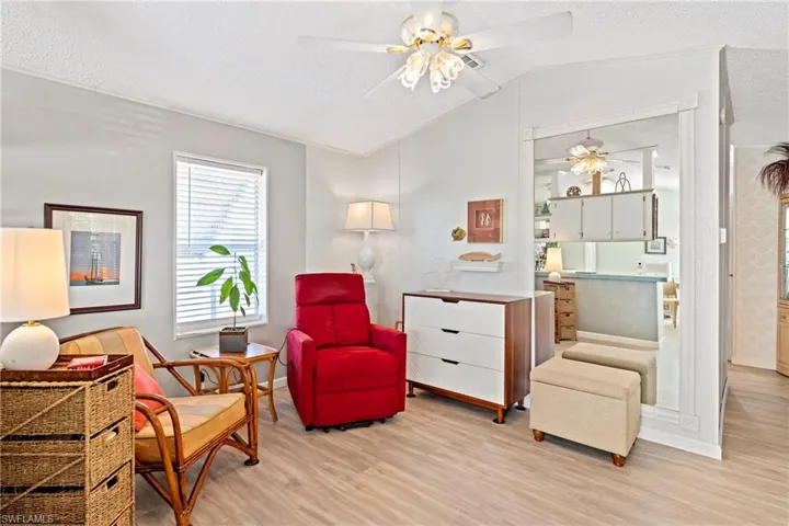 Sitting room with light wood finished floors, a textured ceiling, ceiling fan, and vaulted ceiling