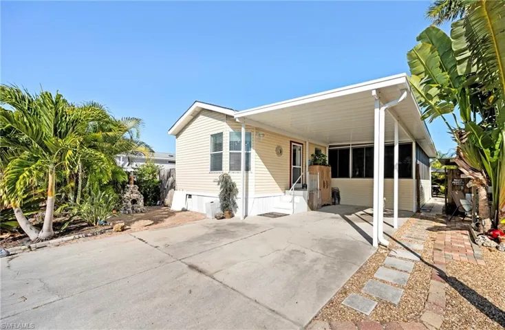 View of front of home with driveway, a carport, a sunroom, and a patio area