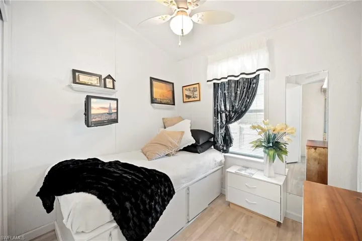 Bedroom featuring light wood finished floors, ceiling fan, ornamental molding, and vaulted ceiling