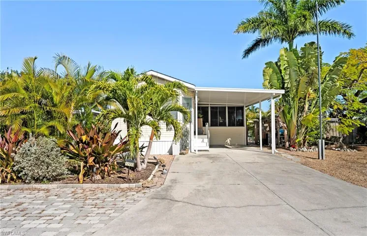 View of front of property featuring a sunroom, concrete driveway, and a carport