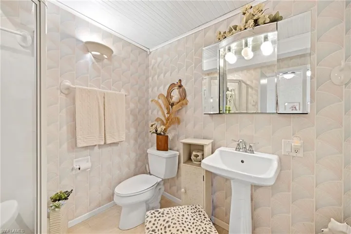 Full bathroom with wallpapered walls and a shower stall