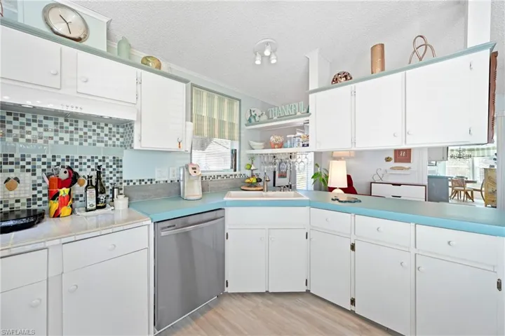 Kitchen featuring light countertops, open shelves, dishwasher, light wood finished floors, and white cabinetry