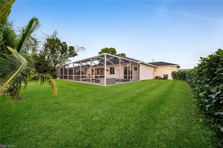 Rear view of property with a lanai and a yard
