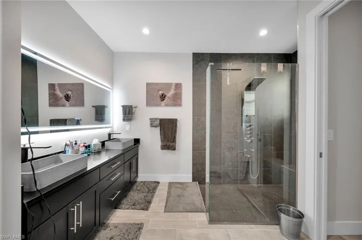 Bathroom with a tile shower, tile patterned flooring, and vanity