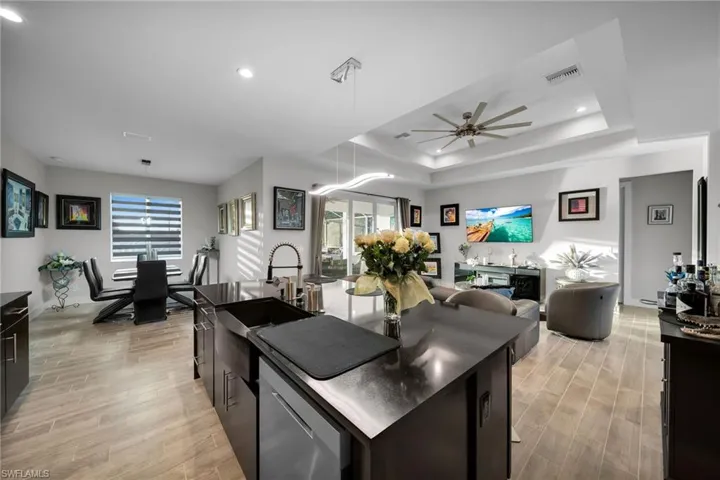 Kitchen with ceiling fan, a center island, a tray ceiling, and light hardwood / wood-style flooring