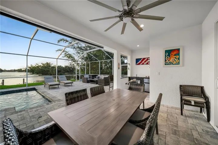 View of patio / terrace featuring a water view, an outdoor living space, ceiling fan, and a lanai