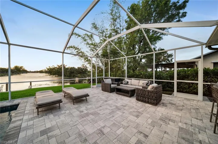 View of patio with glass enclosure, a water view, and an outdoor hangout area