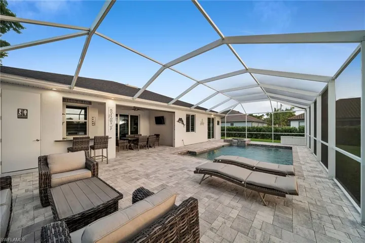 View of swimming pool featuring an outdoor living space, glass enclosure, ceiling fan, and a patio area