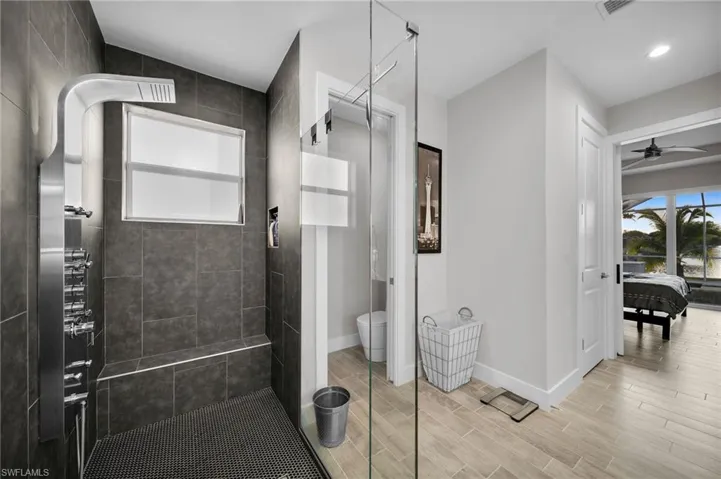 Bathroom featuring a tile shower, ceiling fan, and toilet