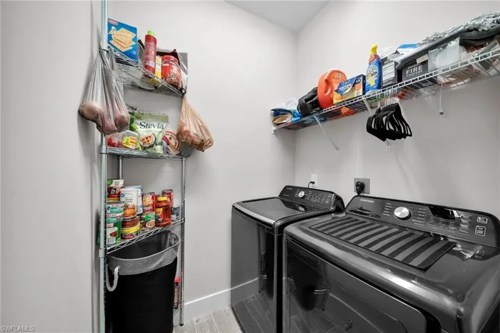 Washroom with hardwood / wood-style floors and washing machine and clothes dryer