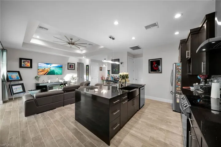 Kitchen with a center island, light hardwood / wood-style flooring, ceiling fan, appliances with stainless steel finishes, and a tray ceiling