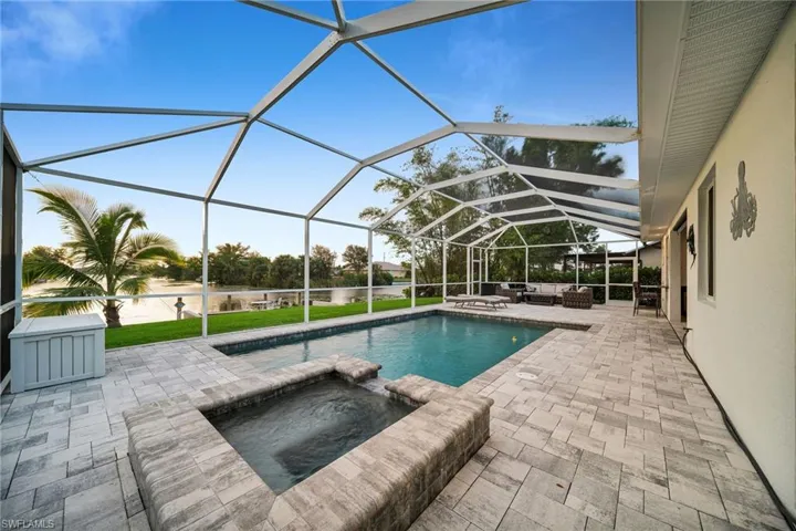 View of pool featuring outdoor lounge area, an in ground hot tub, a patio, and glass enclosure