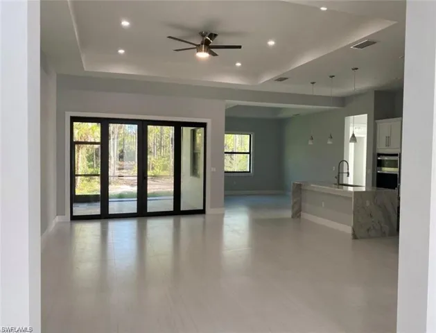 Unfurnished living room with ceiling fan, a tray ceiling, and recessed lighting