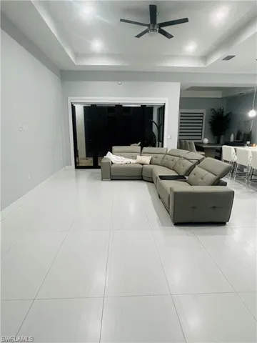 Living room featuring a raised ceiling and a ceiling fan