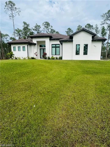Back of property with a lawn and stucco siding