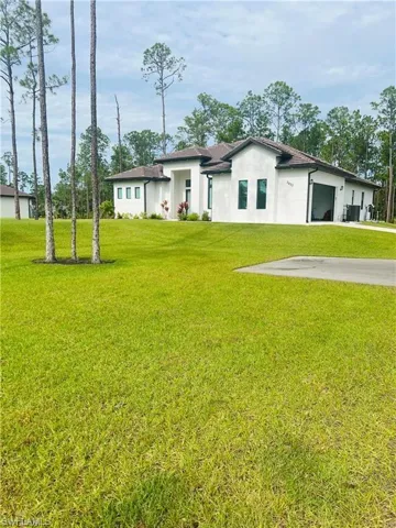 Back of house featuring stucco siding, a yard, and an attached garage