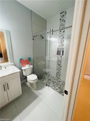 Full bath with a shower stall, vanity, and light tile patterned floors