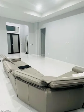 Living area featuring light tile patterned flooring and a raised ceiling