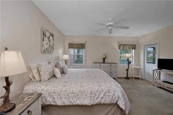 Bedroom featuring ceiling fan, light carpet, and multiple windows
