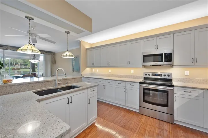 Kitchen featuring ceiling fan, real oak hardwood flooring, sink, granite counters, and stainless steel appliances