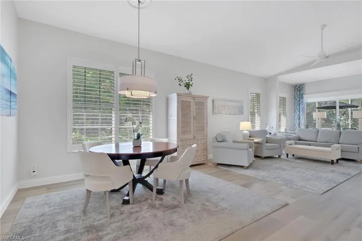 Dining area with light wood-style flooring, vaulted ceiling, and ceiling fan