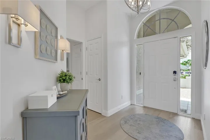 Entrance foyer with plenty of natural light, light wood-type flooring, a chandelier, and a high ceiling