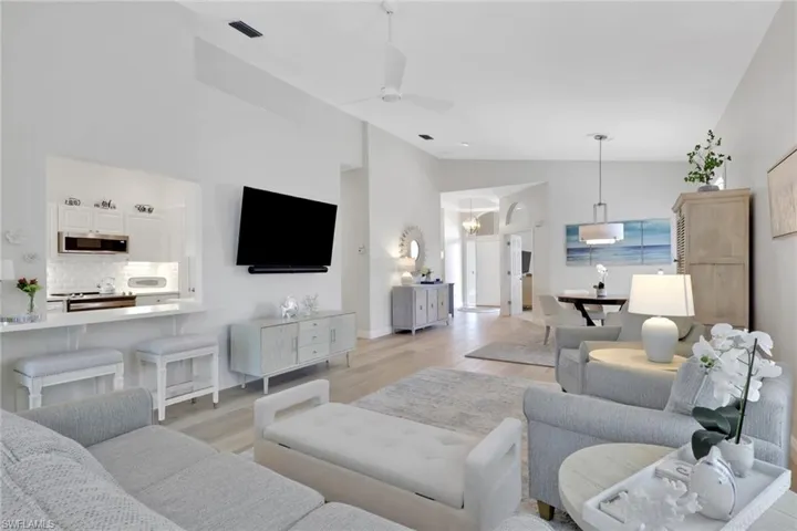 Living room with light wood-type flooring, ceiling fan, vaulted ceiling, and suspended lighting