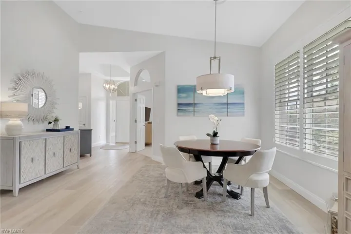 Dining area with vaulted ceiling, light wood-type flooring, and suspended lighting