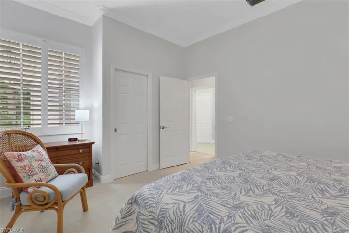 Bedroom featuring light carpet, crown molding, and a closet