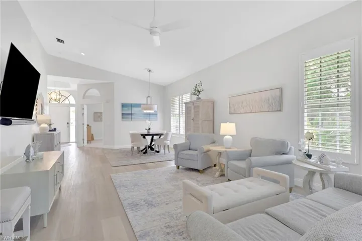 Living room with ceiling fan, light wood-style floors, and vaulted ceiling
