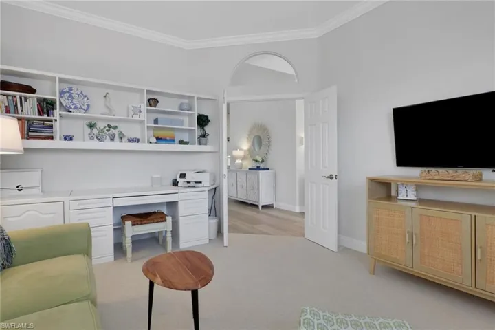 Living room with light carpet, ornamental molding, and built in study area