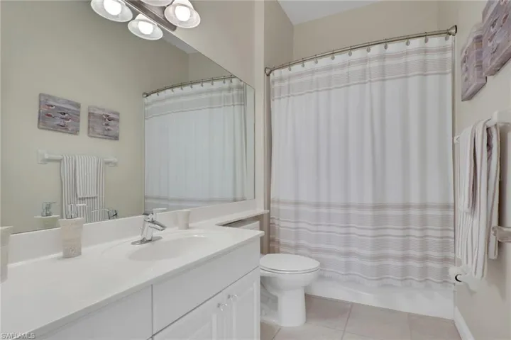 Full bathroom featuring vanity, light tile patterned floors, and shower / bath combo with shower curtain