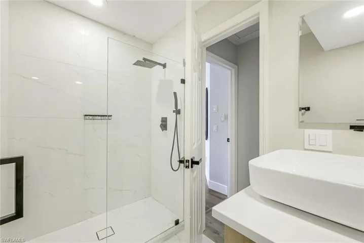 Full bath featuring a marble finish shower, vanity, wood finished floors, and recessed lighting