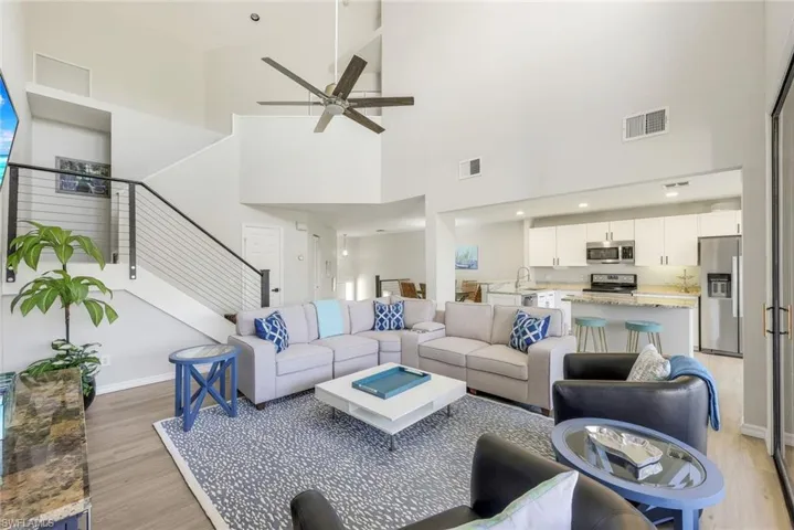Living area featuring stairway, ceiling fan, a towering ceiling, and light wood-type flooring