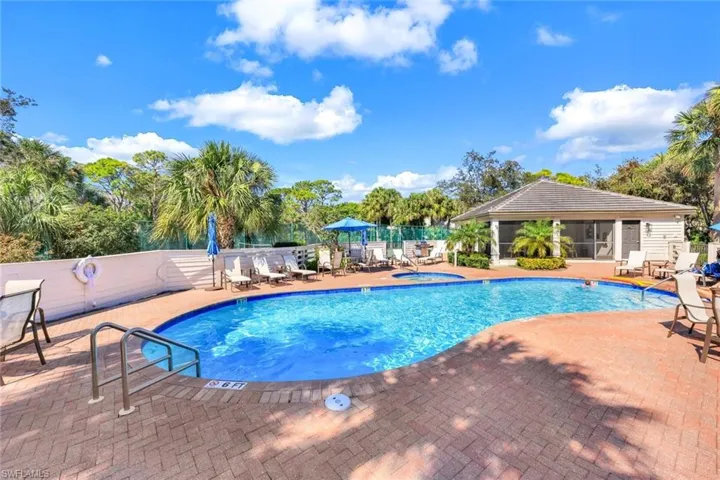 Community pool with a hot tub, a patio, a sunroom/clubhouse , and view of wooded area