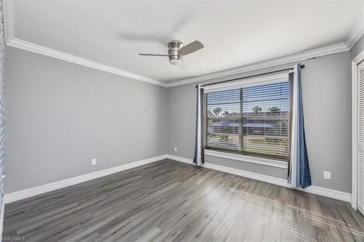 Empty room featuring crown molding, ceiling fan, and wood finished floors