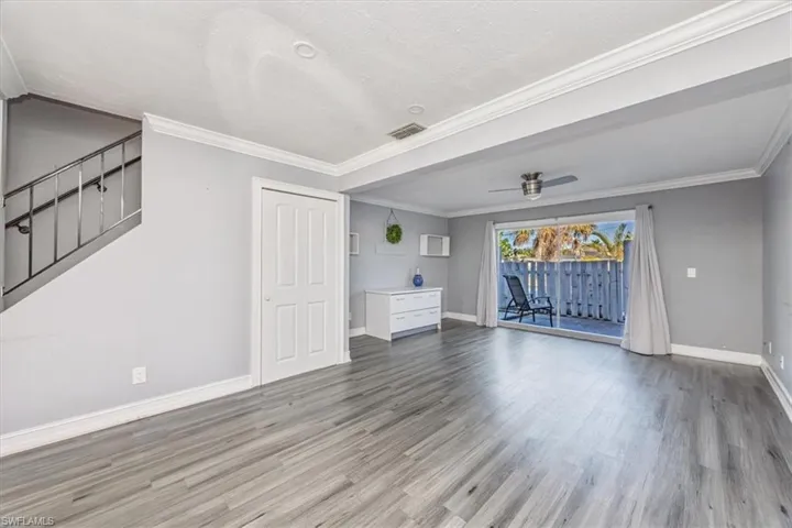 Unfurnished living room featuring ornamental molding, stairway, light wood-type flooring, ceiling fan, and a textured ceiling