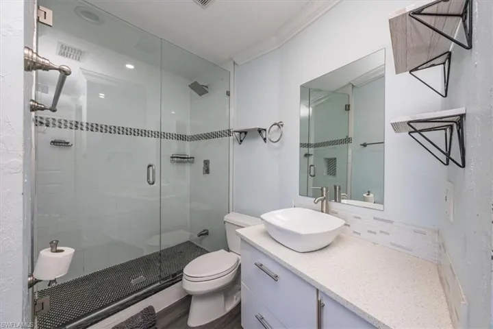 Full bathroom featuring vanity, a stall shower, crown molding, tasteful backsplash, and dark wood finished floors