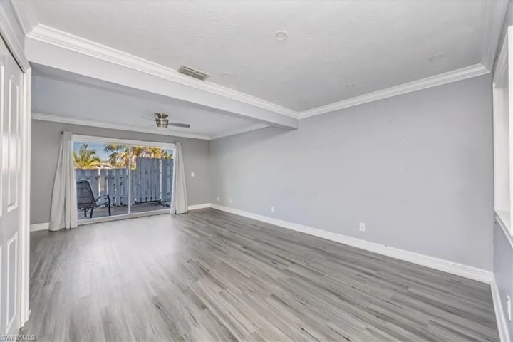 Unfurnished room with crown molding, wood finished floors, a textured ceiling, and a ceiling fan