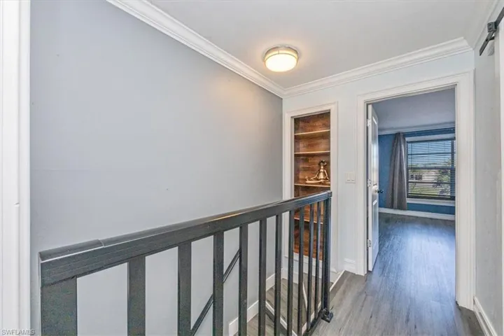 Hallway featuring crown molding, dark wood finished floors, and an upstairs landing