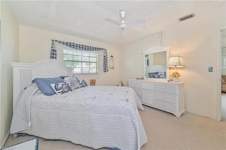 Carpeted bedroom with a textured ceiling and ceiling fan