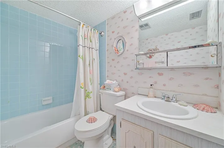 Full bathroom featuring shower / tub combo, tile patterned flooring, a textured ceiling, toilet, and vanity