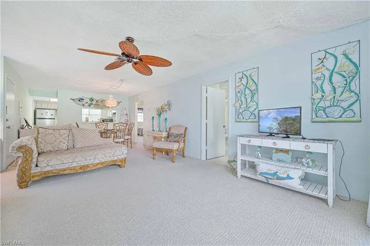 Carpeted living room featuring a textured ceiling and ceiling fan